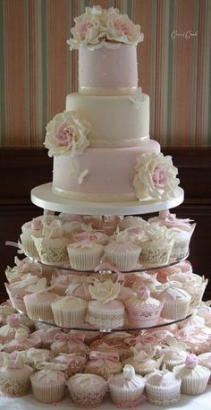 three tiered wedding cake with cupcakes on top