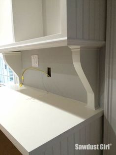 an empty kitchen counter with white cabinets and drawers in the background, there is a yellow cord plugged into the wall