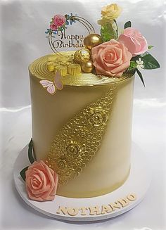 a birthday cake decorated with gold and pink flowers