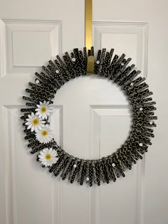 a black and white beaded wreath with daisies hanging on the front door handle