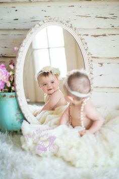 two babies are sitting in front of a mirror