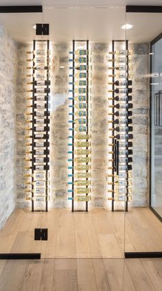 a wine cellar with glass walls and wooden flooring in front of a stone wall