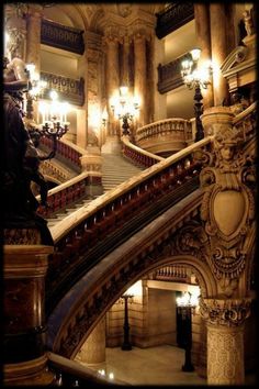 an ornate staircase in a building with chandeliers and statues on the railings