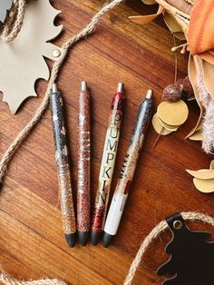 three pens sitting on top of a wooden table next to pumpkins and other decorations