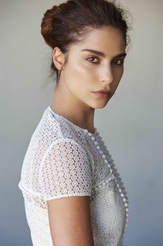 a woman in white shirt and pearls on her head looking at the camera with an intense look