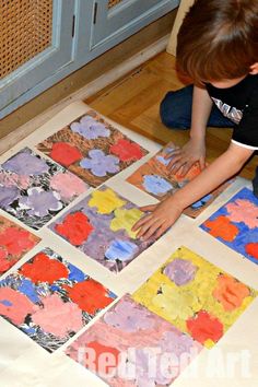 a young boy painting on the floor in front of his artwork work with watercolors