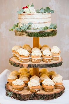 three tiered cake and cupcake display with greenery