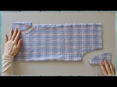 two hands are working on a piece of fabric that has been made into a pillow