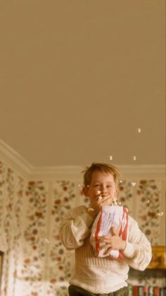 a young boy standing in front of a book shelf with bubbles coming out of his mouth