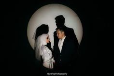 a man and woman dressed up as bride and groom in front of a full moon