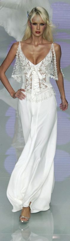 a woman walking down a runway wearing a white dress