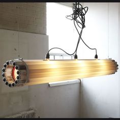 a light fixture hanging from the ceiling in an unfinished room with exposed pipes and wires