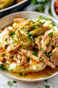 a white plate topped with mashed potatoes covered in chicken and green peppers next to other dishes