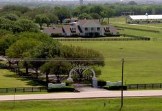 an aerial view of a farm with houses and trees in the foreground, surrounded by lush green grass