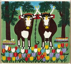 two cows standing next to each other in a field with tulips and trees