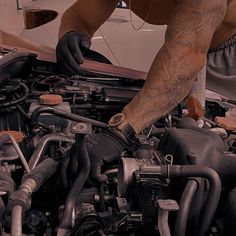 a man working on an engine in a garage with his hands resting on the car's hood