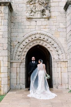 a bride and groom standing in front of an archway