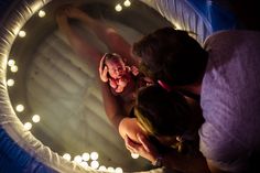 two women and a baby are in a round bathtub with lights on the sides