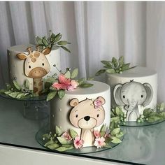 three cakes decorated with animals and flowers on a table