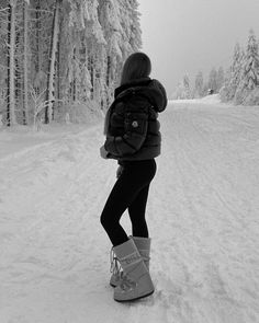 a woman is standing in the snow with her back to the camera and looking at trees