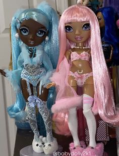 two dolls sitting next to each other on a table