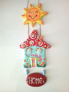 a wall hanging with a house and sun on it