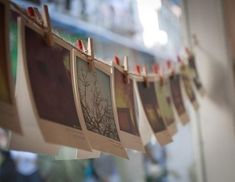 some pictures hanging on a line with clothes pins