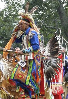 a native american man riding on the back of a horse in front of other people