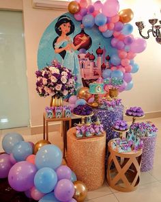 a table topped with lots of purple and blue desserts next to giant balloons in the shape of princesses