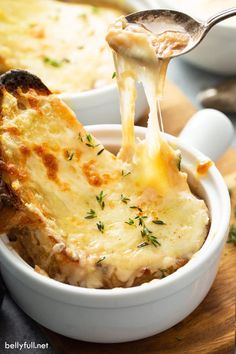 a close up of a bowl of food with cheese being lifted from the side by a spoon