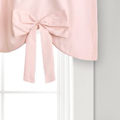 a pink bow tie valance hanging on the side of a white window sill