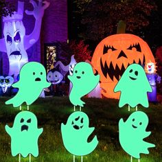 halloween yard decorations in the shape of ghostes and pumpkins at night with lights