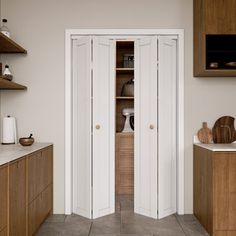 two white doors open in a kitchen with wooden cabinets and counter tops on both sides