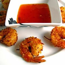 some shrimp sticks are on a white plate and sauce is in a small square bowl