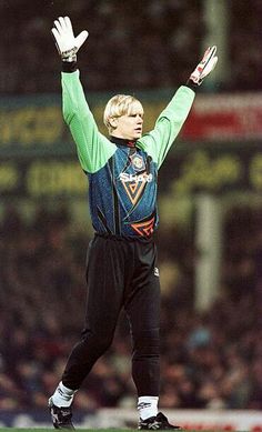 a man with his hands up in the air while standing on top of a soccer field