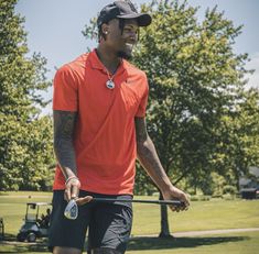 a man in an orange shirt and black shorts holding a golf club