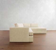 a white couch sitting on top of a wooden floor next to a chair and ottoman