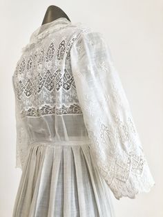 "Antique Edwardian white cotton lawn dress has eyelet lace embroidery throughout the bodice, sleeves, and around the hem. The dress has a ruffle trimmed net collar and net under bodice that has a crossover snap detail. The dress has snap and hook and eye closures at the skirt and bodice. Condition Overall excellent. There's a repair to the right sleeve, and orange stains near the seam. The front skirt has stains at the hem, the back skirt has some stains near the top of the lace, and yellowing a Broderie Anglaise Long Sleeve Day Dress, Classic Broderie Anglaise Dresses For Daytime, Classic Broderie Anglaise Dresses For Daywear, Classic Dresses With Broderie Anglaise For Daywear, Classic Broderie Anglaise Dresses, Victorian Ruffle Dress For Spring, Spring Victorian Ruffle Dress, Classic Victorian Dress With Lace Trim For Spring, Spring Broderie Anglaise Cotton Lace Dress