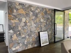 a living room with a stone wall and glass doors