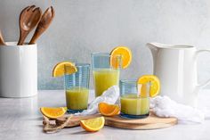 orange juice in glasses with spoons and utensils next to them on a table