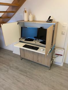 a desk with a computer monitor and keyboard on it in front of a stair case