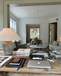 a living room filled with lots of furniture and books on top of a wooden table