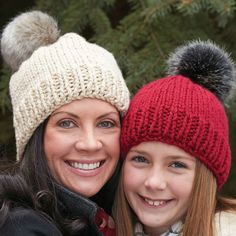 two women are posing for the camera with their arms around each other, both wearing winter hats and scarves