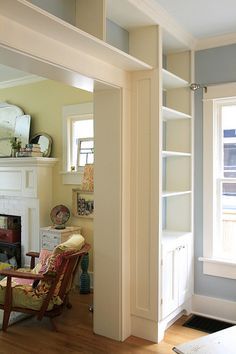 a living room filled with furniture and a fire place under a window on top of a hard wood floor