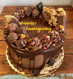 a large chocolate cake sitting on top of a wooden table next to a sign that says happy thanksgiving