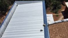 an overhead view of the roof of a house with metal sheeting on it and two workers working on the roof