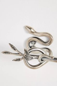 a silver snake brooch with an arrow on it's back and two leaves attached to the clasp