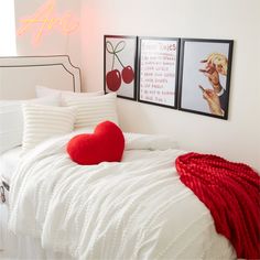 a bed with two pictures on the wall above it and a heart shaped pillow sitting on top of it