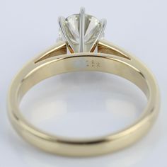 a yellow gold engagement ring with a single diamond in the center, on a white background