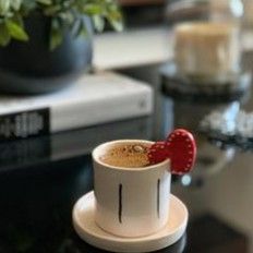 a coffee cup with a red heart on it sitting on top of a saucer